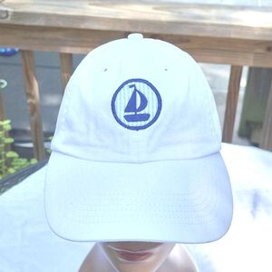 White cap, navy sailboat on light blue seersucker background,  adjustable back